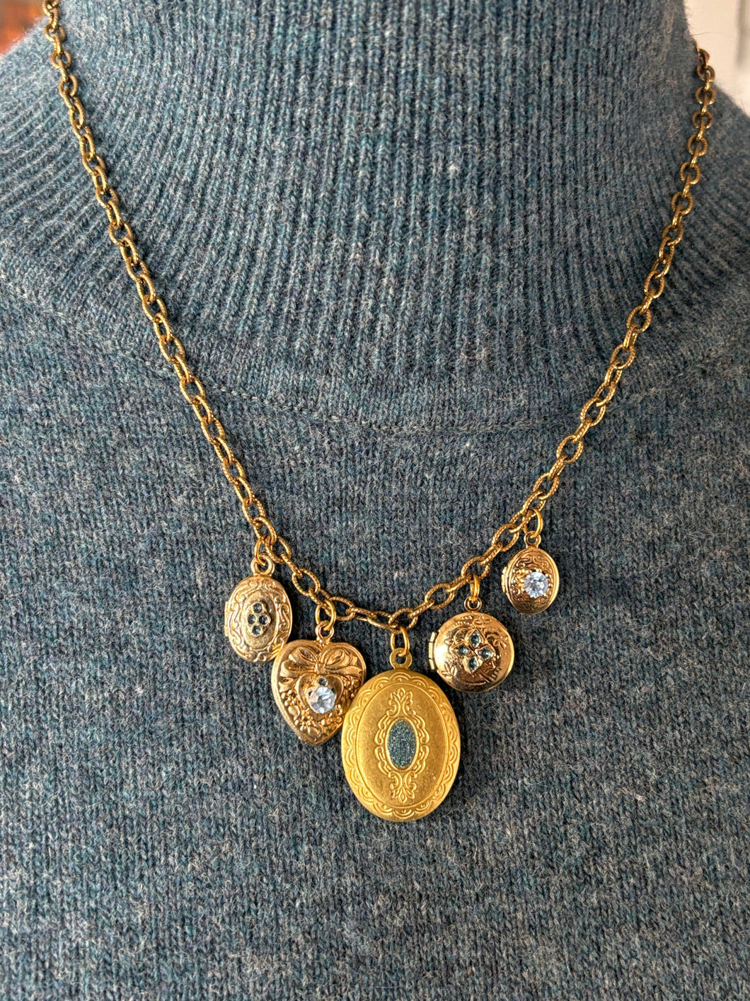 Gold locket charm necklace on a gray sweater