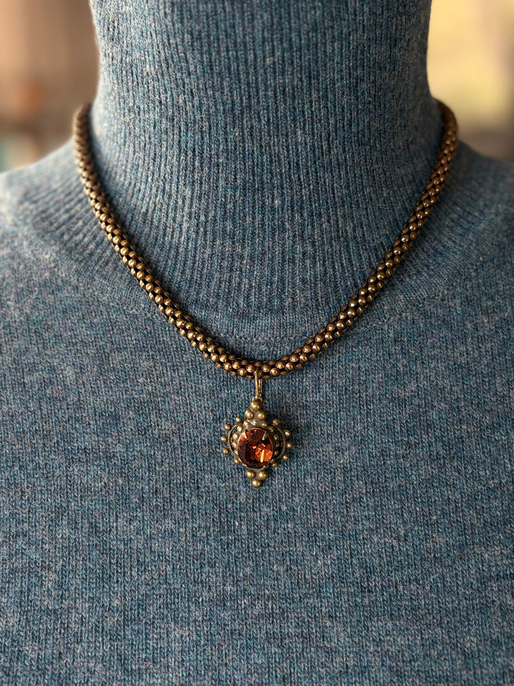 Edwardian inspired Brass Necklace with a pendant on a mannequin wearing a blue sweater