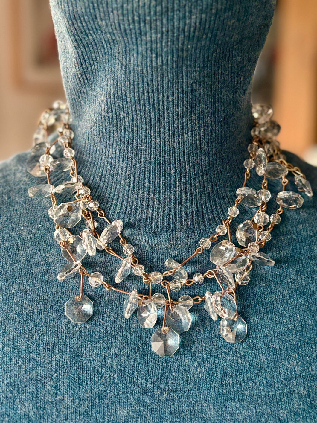 Crystal quartz Necklace with gold accents on a blue textured surface