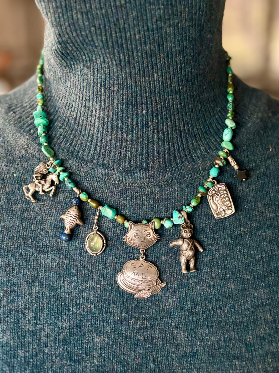 sterling Necklace with charms on a mannequin wearing a dark green sweater