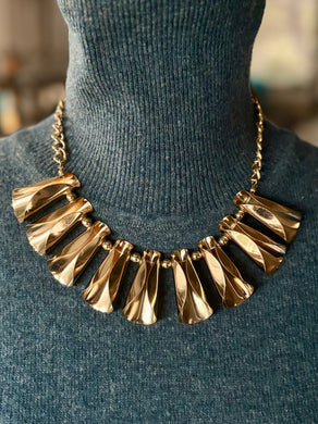 Gold tone egyptian inspired necklace on a mannequin with a blurred background