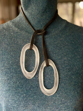 Necklace with large lucite oval pendants on a mannequin wearing a blue sweater.