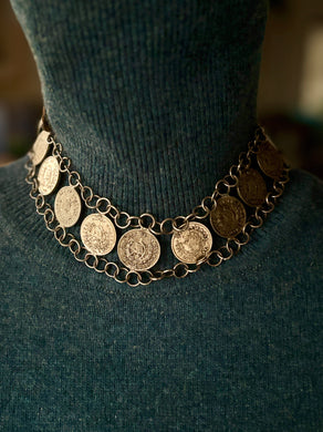 Necklace with coin pendants on a dark green sweater