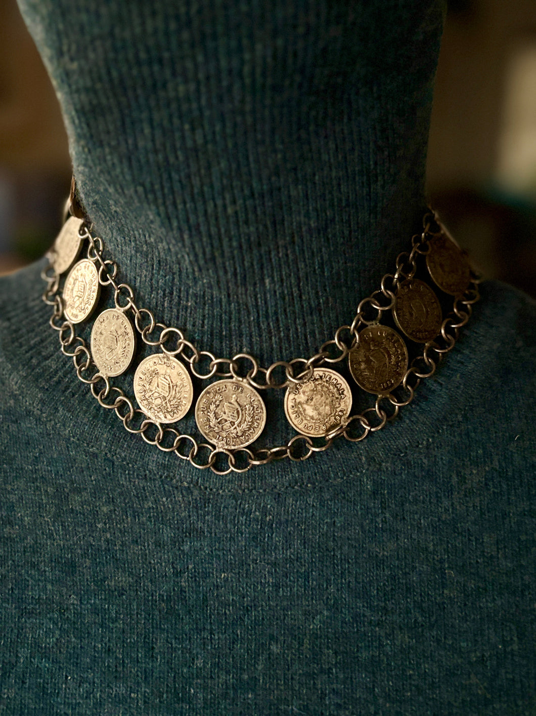 Necklace with coin pendants on a dark green sweater